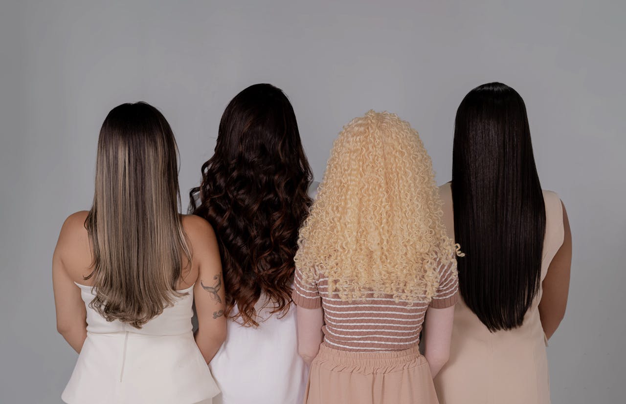 Crafting Captivating Headlines: Your awesome post title goes here Four women showing diverse hairstyles from behind, emphasizing hair texture and color.
